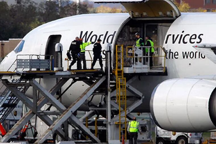 Investigators board a United Parcel Service jet isolated on a runway at Philadelphia International Airport on Friday. Law enforcement officials are also investigating reports of suspicious packages on a cargo plane in Newark. (AP Photo / Matt Rourke)