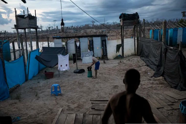 In this March 31, 2019 photo, police officers rise early in the morning at the Balata police and military base in Peru's Tambopata province. The base occupied by "Operation Mercury" security forces is surrounded by two lakes contaminated with mercury, as well as debris left over by miners. (AP Photo/Rodrigo Abd)