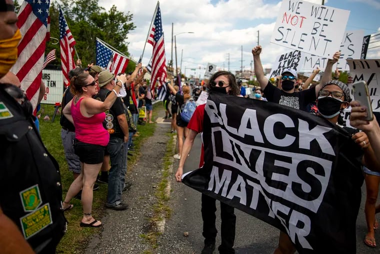 Protesters march by locals, bikers, and Trump supporters who were counter-protesting a Black Lives Matter march in Ridley on Aug. 1.