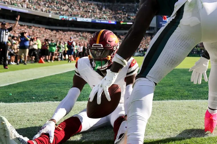 Eagles wide receiver A.J. Brown gives Washington Commanders cornerback Emmanuel Forbes his touchdown ball after scoring during the 4th quarter on Sunday, October 1, 2023 in Philadelphia. Brown received a taunting penalty for the action.