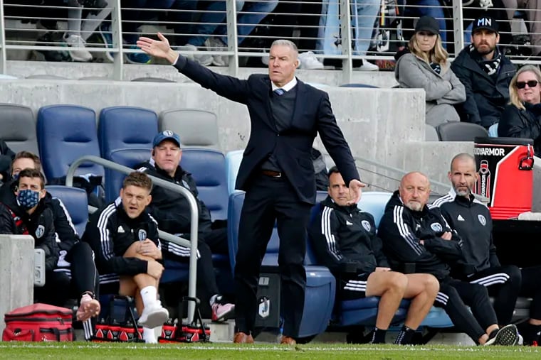 Sporting Kansas City manager Peter Vermes in front of his team's bench, signaling for something other than a first down.