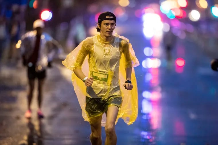 Brendan Shearn, from Philadelphia, warms up in the cold and rain as he jogs out on the Benjamin Franklin Parkway with his rain poncho on prior to the start of the Philadelphia Marathon in 2019. Sunday should be way better.