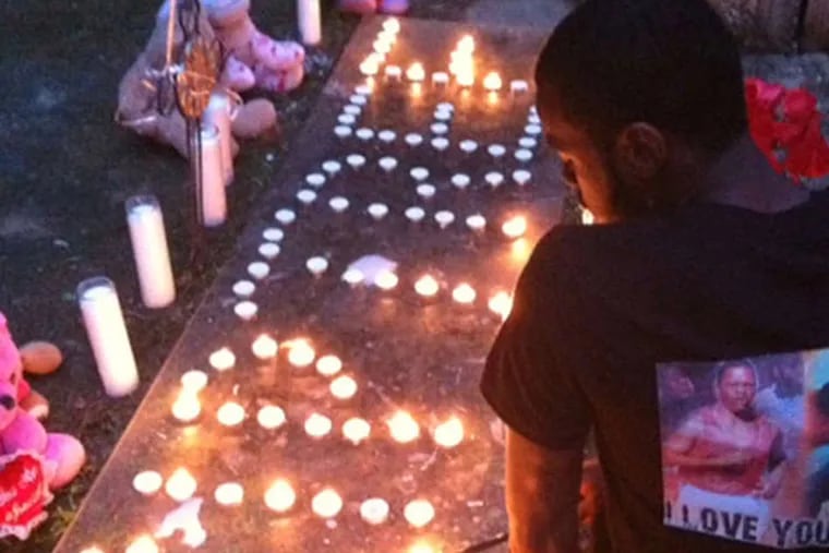 Tremaine Rogers' brother, Aaron, lights candles that spell 'RIP TREE' during a vigil Sunday night. (Stephanie Farr/Staff)