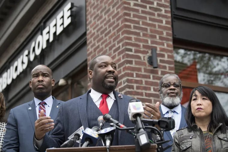 Philadelphia City Councilman, Kenyatta Johnson, center, flanked by two fellow members, speaks at the podium during a press conference outside the Starbucks on 18th and Spruce Streets.