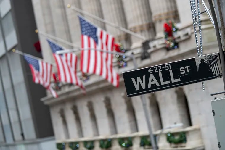The Wall St. street sign is framed by U.S. flags flying outside the New York Stock Exchange in New York.