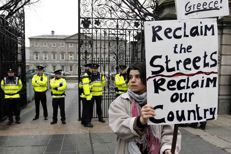 A protester carries a sign outside Leinster House in Dublin. Lawmakers voted on Wednesday to back a 67.5 billion-euro international rescue despite high interest rates from EU partners.