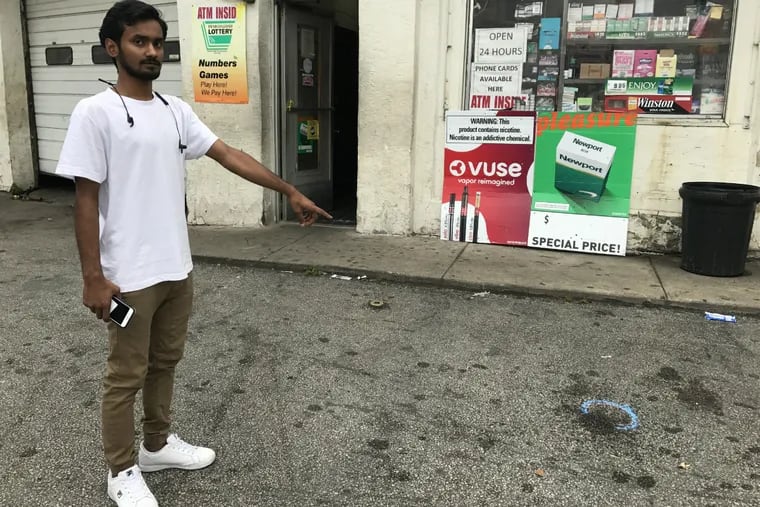 Sajjad Hossain points to where police recovered one of 16 fired cartridge casings at the Gulf gas station lot on Passyunk Avenue, near 25th Street, in South Philadelphia, where two 15-year-old boys were shot, one fatally, about 8 p.m. Thursday, Oct. 4, 2018.