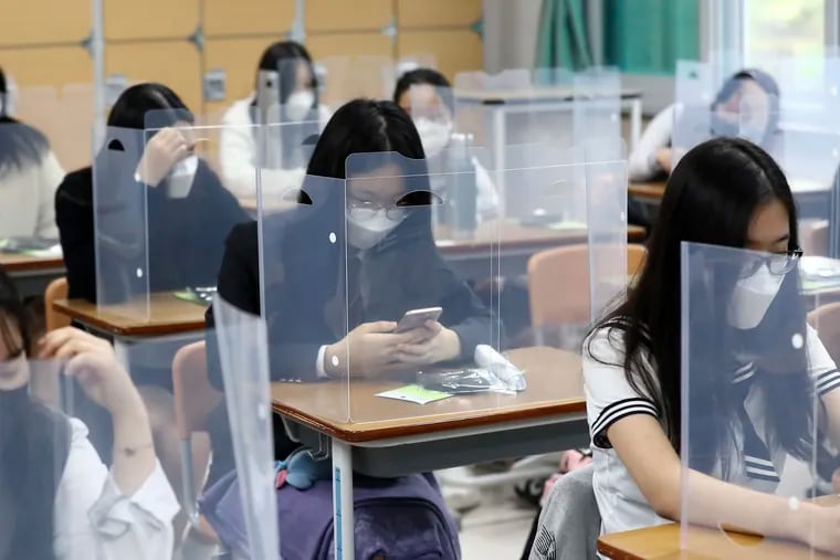 Senior students wait for class to begin with plastic boards placed on their desks at Jeonmin High School in Daejeon, South Korea South Korean students began returning to schools last week as their country prepares for a new normal amid the coronavirus pandemic.