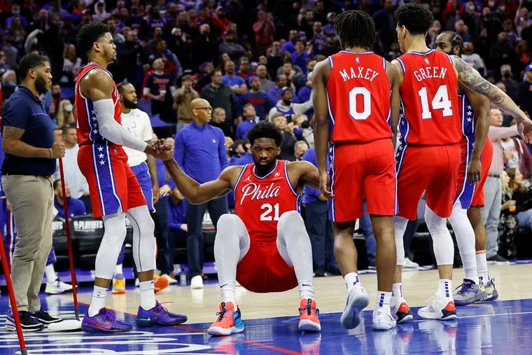 Sixers center Joel Embiid gets help getting off the floor from his teammates after getting fouled against the Toronto Raptors.