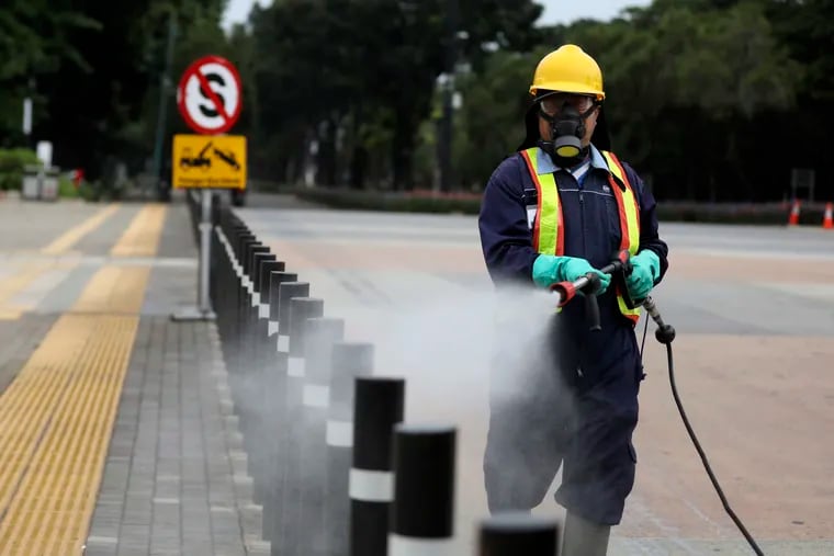 A worker sprays disinfectant at the pedestrian walkway at Senayan Sports Complex amid the coronavirus outbreak in Jakarta, Indonesia.