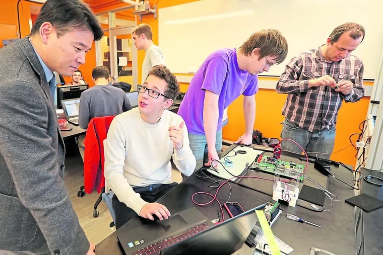 Rowan University assistant professor Sangho Shin (left), who oversees the MemSat Project, talks with Tomas Uribe, who is writing code to measure battery duration.