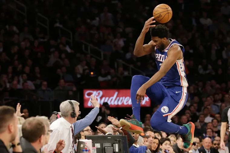 76ers star Joel Embiid leaps into the stands while chasing a loose ball during the second half of the team's 126-111 victory over the Knicks.