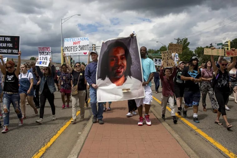 Protesters carry an image of Philando Castile as they march on Sunday, June 18, 2017, in St. Anthony, Minn., after the acquittal of the local police officer who shot Castile during a traffic stop.