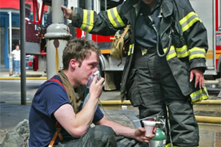 Unidentified firefighter, given oxygen by a paramedic, was one of many who were affected by the intense heat and smoke they encountered trying to gain entry into the burning building.