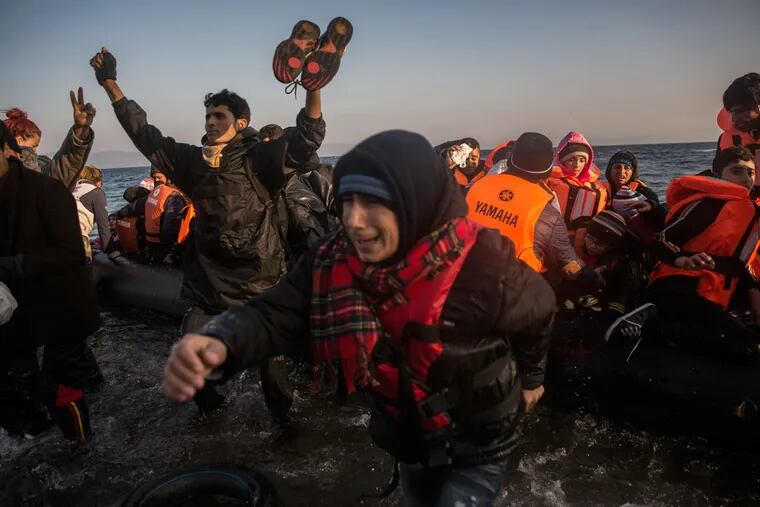 Refugees and migrants react as they disembark from a dinghy after their arrival from the Turkish coast to the northeastern Greek island of Lesbos on Tuesday, Nov. 17, 2015.
