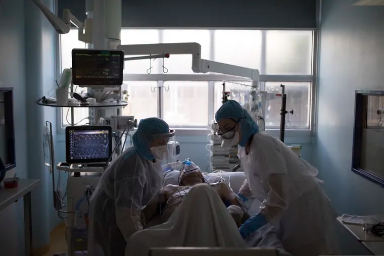 Healthcare workers assist a COVID-19 patient in the intensive care unit at the Joseph Imbert Hospital Center in Arles, southern France, Wednesday, April 15, 2020.