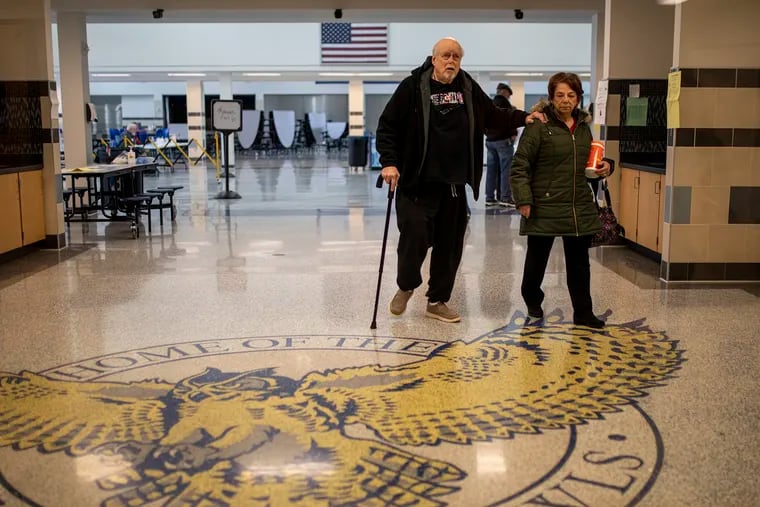 Marlene Alpaugh, 72, of Bensalem, Pa., right, helps her husband Richard Alpaugh, 73, walk out after voting in a Bucks County special election for a state House seat at Bensalem High School on March 17, 2020.