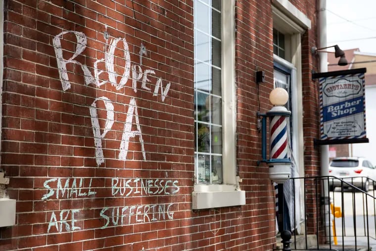 Nichole Missino, owner of Giovanni’s Media Barber Shop, has chalk on the front of her building reading, “ReOpen PA, small businesses are suffering."