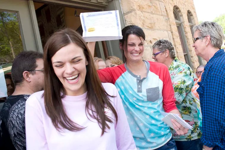 Kristin Seaton holds up her marriage license - the state's first - as she leaves the courthouse in Eureka Springs, Ark., with her partner, Jennifer Rambo.