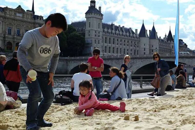 In this July 20, 2012 file photo, children play in sand during the Paris Plages event in Paris, featuring palm trees, sand beaches, hammocks, lounge chairs, volley ball courts and a pool line the 3.5-kilometer (2.2-mile) riverside attraction. Paris Plages or Paris Beaches, is a free summer event that transforms several spots along the Seine river into complete beaches.  (AP Photo/Thibault Camus, File)