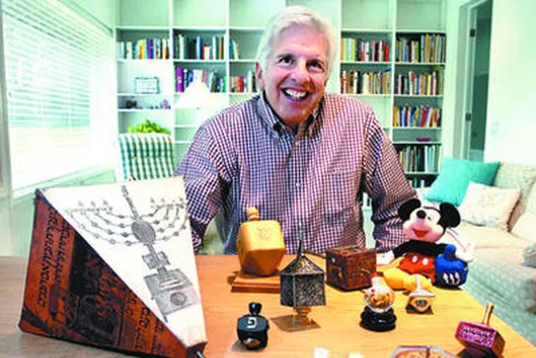 Morton Langsfeld in his Abington home with favorites from his collection of 127 dreidels, a toy associated with Hanukkah. "Dreidels just always brought happy thoughts to me," he says. (Ron Tarver / Staff Photographer)