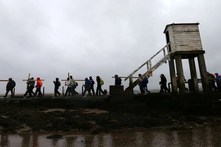In England , pilgrims make the final leg of a 100-mile journey to Holy Island, Berwick Upon Tweed. The faithful have made the Holy Week trek for three decades. AP