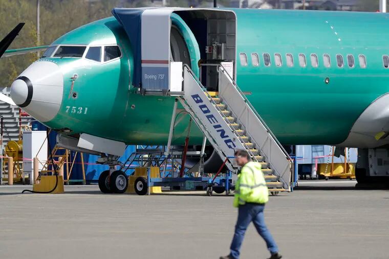 In this April 26, 2019, file photo a worker walks past a Boeing 737 MAX 8 airplane being built for Oman Air at Boeing's assembly facility in Renton, Wash.