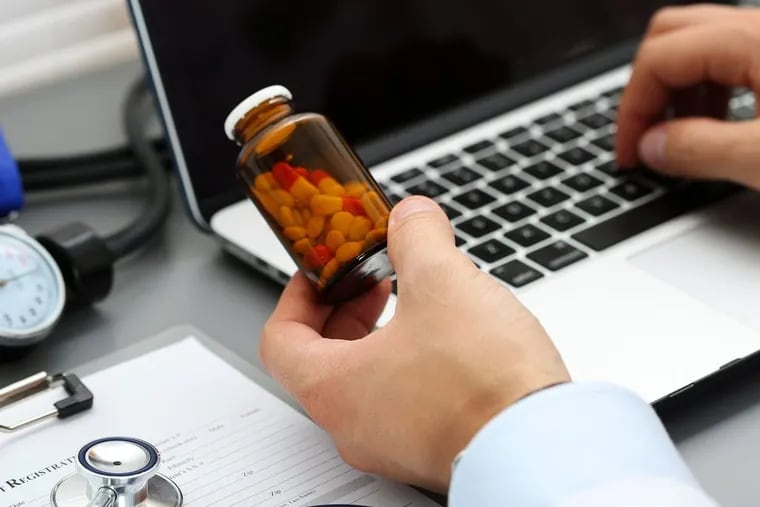 Male medicine doctor hands hold jar of pills and type something on laptop computer keyboard. Panacea and life save, prescribing treatment, legal drug store, take stock, consumption statistics concept