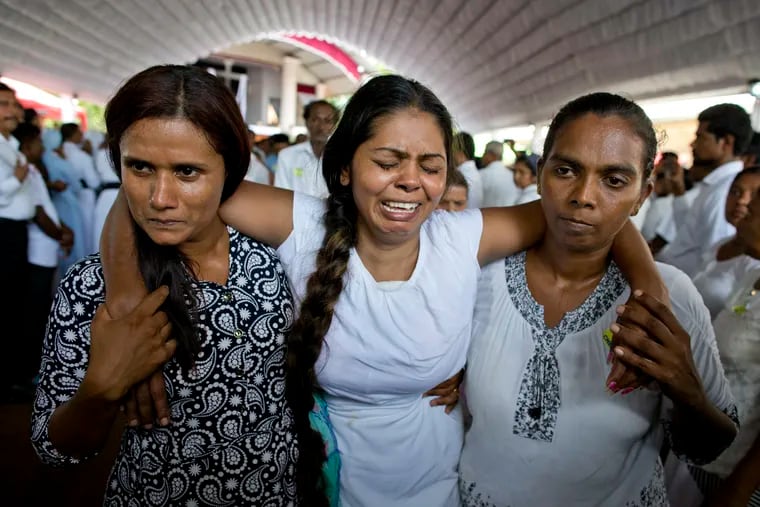 A grieving woman is supported during a funeral service attended by Cardinal Malcolm Ranjith for Easter Sunday bomb blast victims at St. Sebastian Church in Negombo, Sri Lanka, Tuesday.