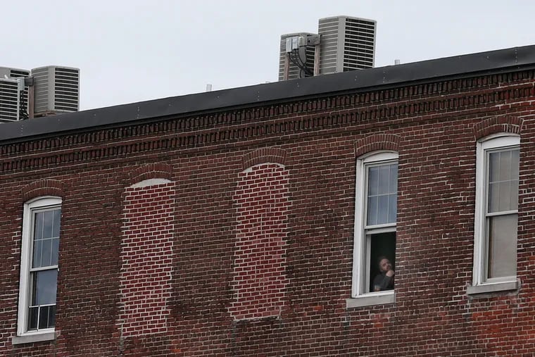 A man looks out of an apartment building in Philadelphia's Fishtown section on Wednesday, April 1, 2020. The city has directed residents to stay at home except for essential activities.