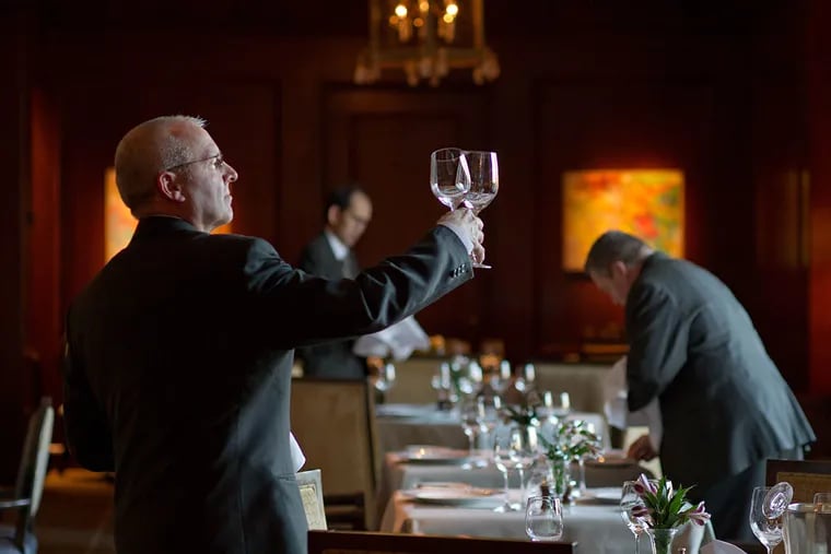 Jim Miller, a server at the Fountain since it opened in July 1983, examines glasses as fellow servers prepare the dining room.
