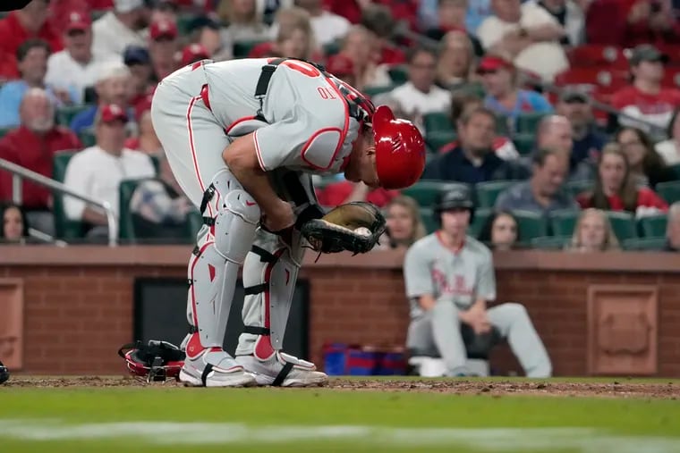 Phillies catcher J.T. Realmuto doubles over after taking a pitch to the throat during the seventh inning of Tuesday's game in St. Louis.