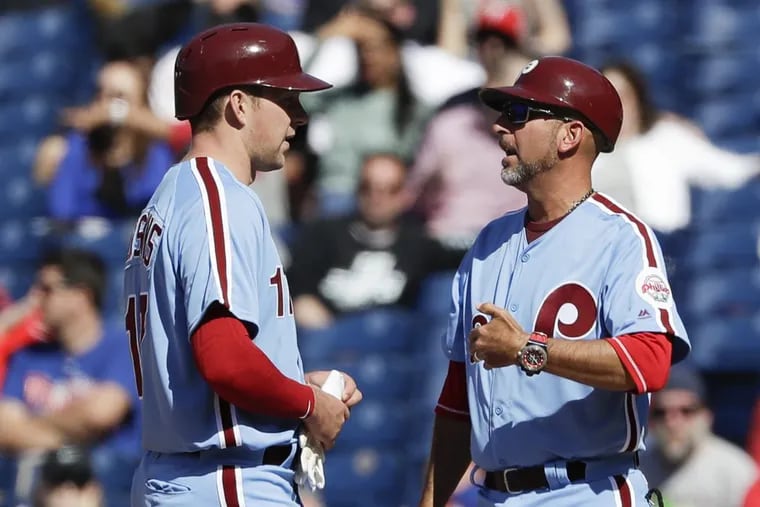 First-base coach Jose David Flores talks to Rhys Hoskins (left) during Thursday’s game against the Diamondbacks.