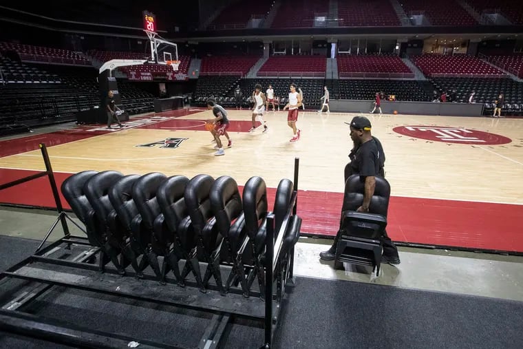 Lamarr Ellison works putting folding chairs away after the Temple/Drexel basketball game was postponed due to members of the Drexel team entering COVID-19 protocols.  The game was to have been played at Temple's  Liacouras Center on Dec. 18, 2021.  Temple players play a pickup game in the background.