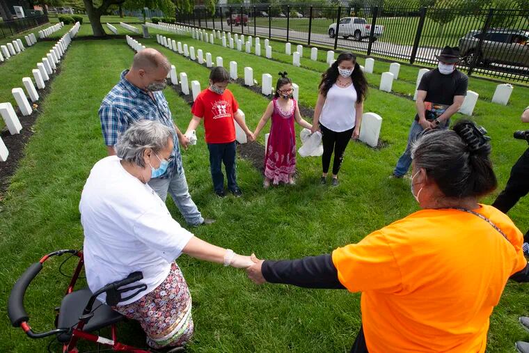 Karen Collins, (left) an elder from the American Indian Society, leads the group in prayer on May 23, 2020.  They usually number about 50, but because of the corona virus had to keep the tradition alive with a smaller group. A group of Native Americans have come every Memorial Day weekend since 1973 to the cemetery of the Carlisle Indian Industrial School at the Carlisle Barracks to honor the students who died while attending school there and to decorate their graves.