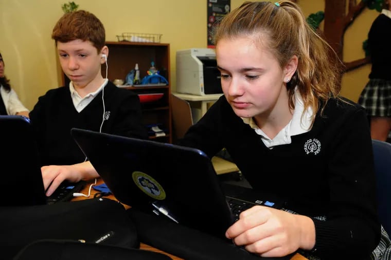 Eighth graders Chip Opdahl and Clare Gimpel work on computer assignments in the News Literacy Project class at Norwood-Fontbonne Academy in Chestnut Hill.