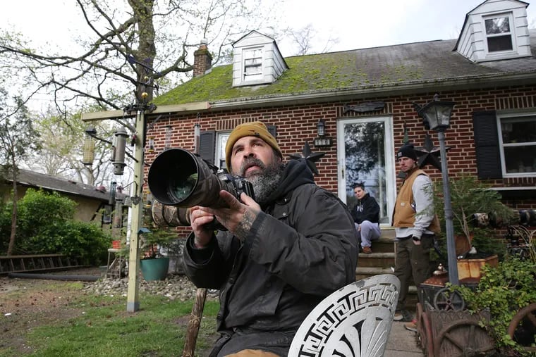 Photographer and tattoo artist Rick Fichter spots a cardinal outside his home in Cherry Hill. Watching in the background is his wife, Leah Fichter, and coworker Rich Koch (right).
