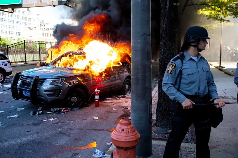 A Pennsylvania State Trooper stands guard as a burning police vehicle is behind him during protests for the death of George Floyd on Saturday.