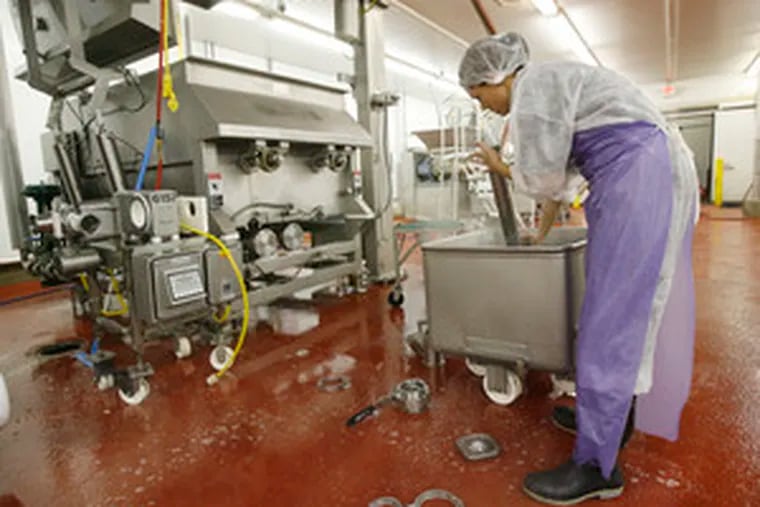 After a day of production, machine operator Litza Flores cleans piping from the cooker on the left that blends ingredients and then slow-cooks the dog food at Freshpet&#0039;s Quakertown plant.