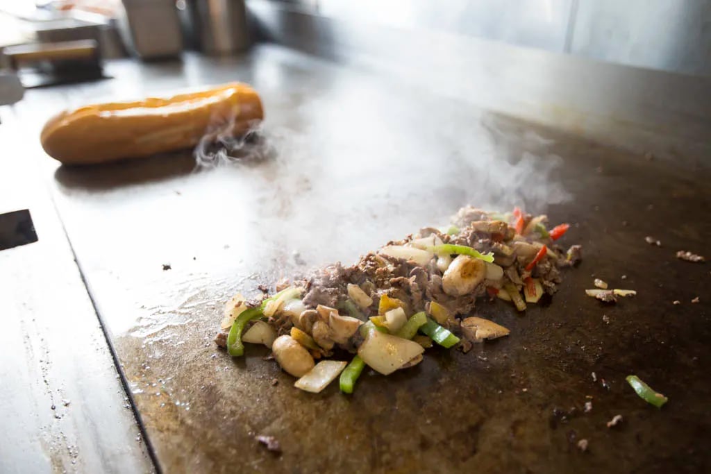 Steak, mushrooms, peppers and onions on the grill at Sumo Steaks. ( Colin Kerrigan / Philly.com )