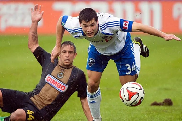 Impact's Karl Ouimette, right, is brought down by Philadelphia Union's Danny Cruz during the first half of an MLS soccer game in Montreal, Saturday, April 26, 2014. (AP Photo/The Canadian Press, Graham Hughes)