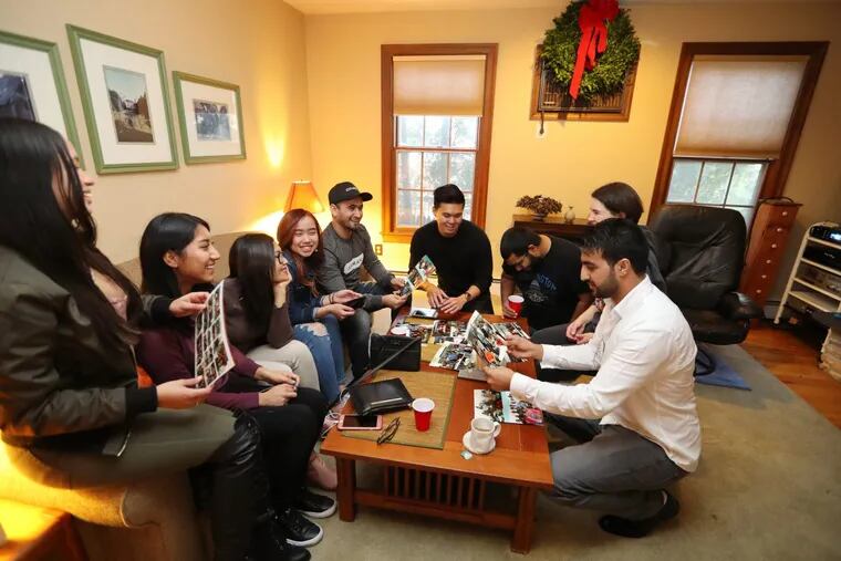 Students gather before eating and look over photographs as David Hodges, director of the Collingswood Farmers Market, hosts his second annual Thanksgiving for ESL students.