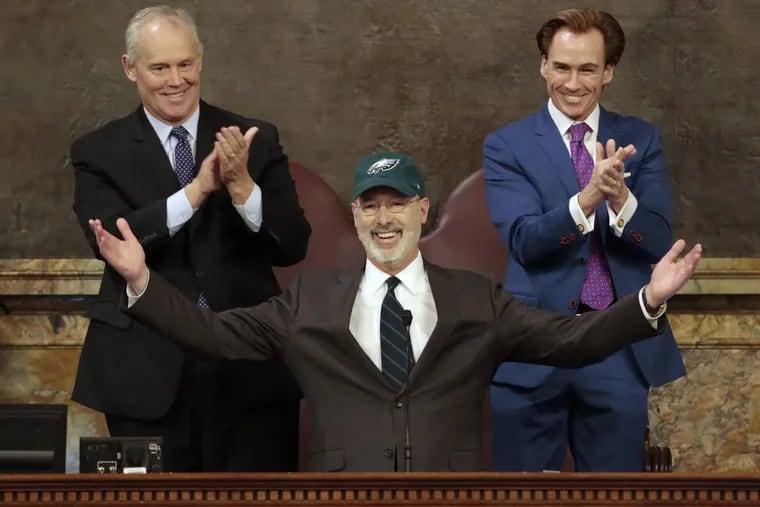 Democratic Gov. Tom Wolf puts on a Philadelphia Eagles hat to celebrate their Super Bowl win before he gives his budget address at the state Capitol in Harrisburg, Pa., on Tuesday, Feb. 6, 2018.
