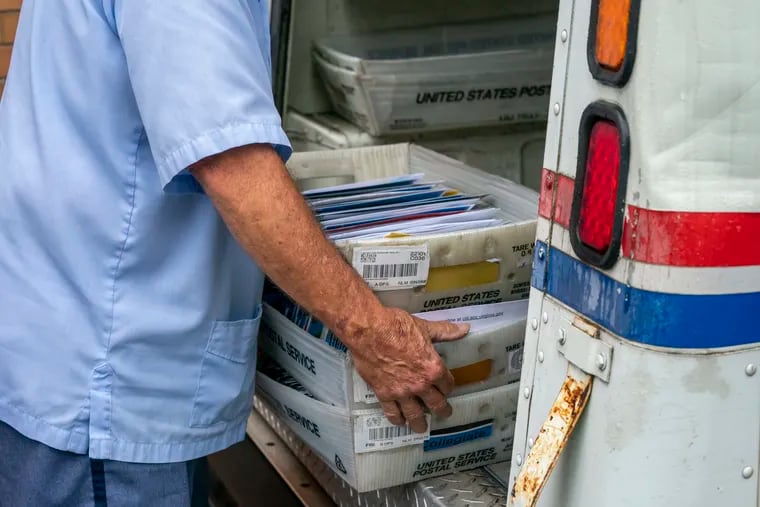 Letter carriers load mail trucks for deliveries at a U.S. Postal Service facility in McLean, Va., Friday, July 31, 2020.