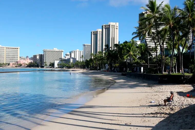 This October 2020 photo shows a man sitting on a nearly empty Waikiki Beach in Honolulu.