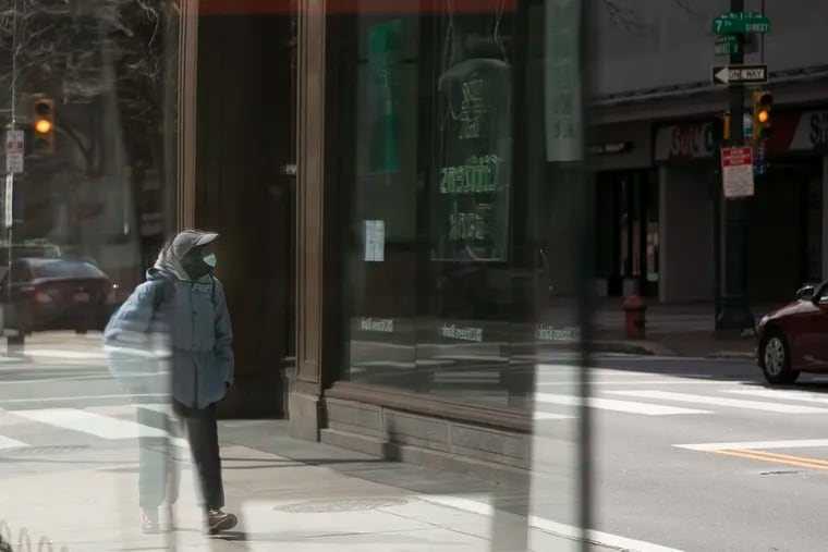 A pedestrian in a mask walks along Market Street near Seventh Street in Philadelphia in March early in the city's shutdown due to the spread of the coronavirus.