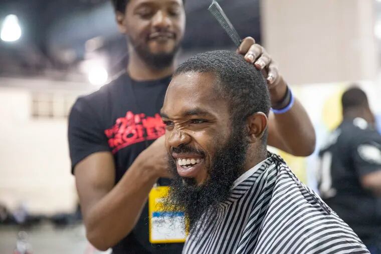 Marquise DuPont gets his hair cut by Marcus Harmon at the Hire! Philly Job and Resource Fair at the Convention Center on Thursday. Starbucks led the charge to organize a group of Philly employers who put on the event.