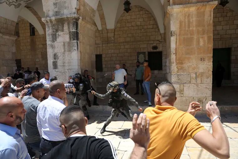 Israeli border police swing their batons at Muslim worshippers gathered for Friday prayers at the Dome of the Rock Mosque in the Al-Aqsa Mosque compound in the Old City of Jerusalem, Friday, May 14, 2021.