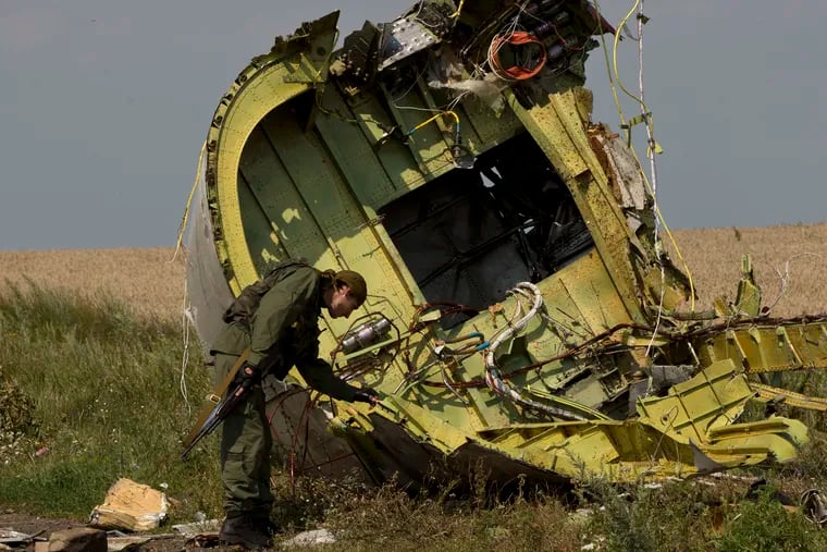In this July 22, 2014 file photo, a pro-Russian rebel touches the MH17 wreckage at the crash site of Malaysia Airlines Flight 17, near the village of Hrabove, eastern Ukraine. The Dutch foreign minister said Thursday Feb. 7, 2019, that the Netherlands is in diplomatic discussions with Russia about his country’s assertion that Moscow bears legal responsibility for the downing of a Malaysian passenger jet over Ukraine in 2014.