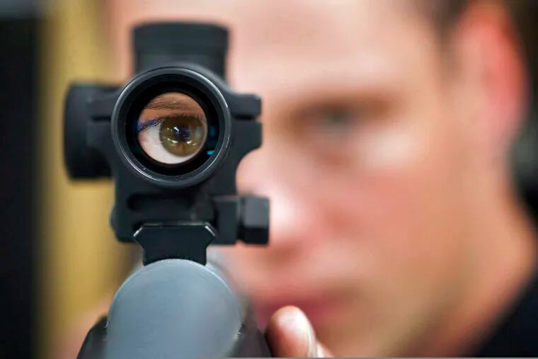 FILE - In this Sept. 15, 2010 file photo, an employee looks through the scope of long gun at a gun store in Calgary, Alberta, Canada. When Canada first sought to restrict gun access in the 1990s, the National Rifle Association threatened a boycott by U.S. hunters spending tourism dollars in the country. (Jeff McIntosh/The Canadian Press via AP)